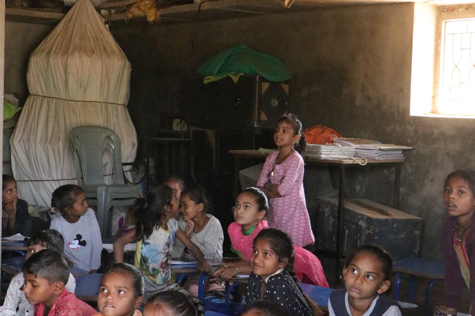 Children sitting on the floor of a classroom, writing in notebooks