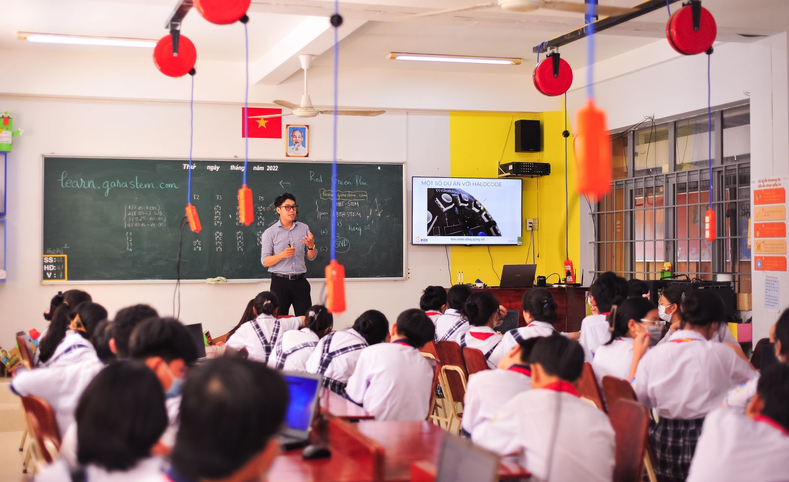A teacher at the front of a classroom leading a lesson with students at their desks